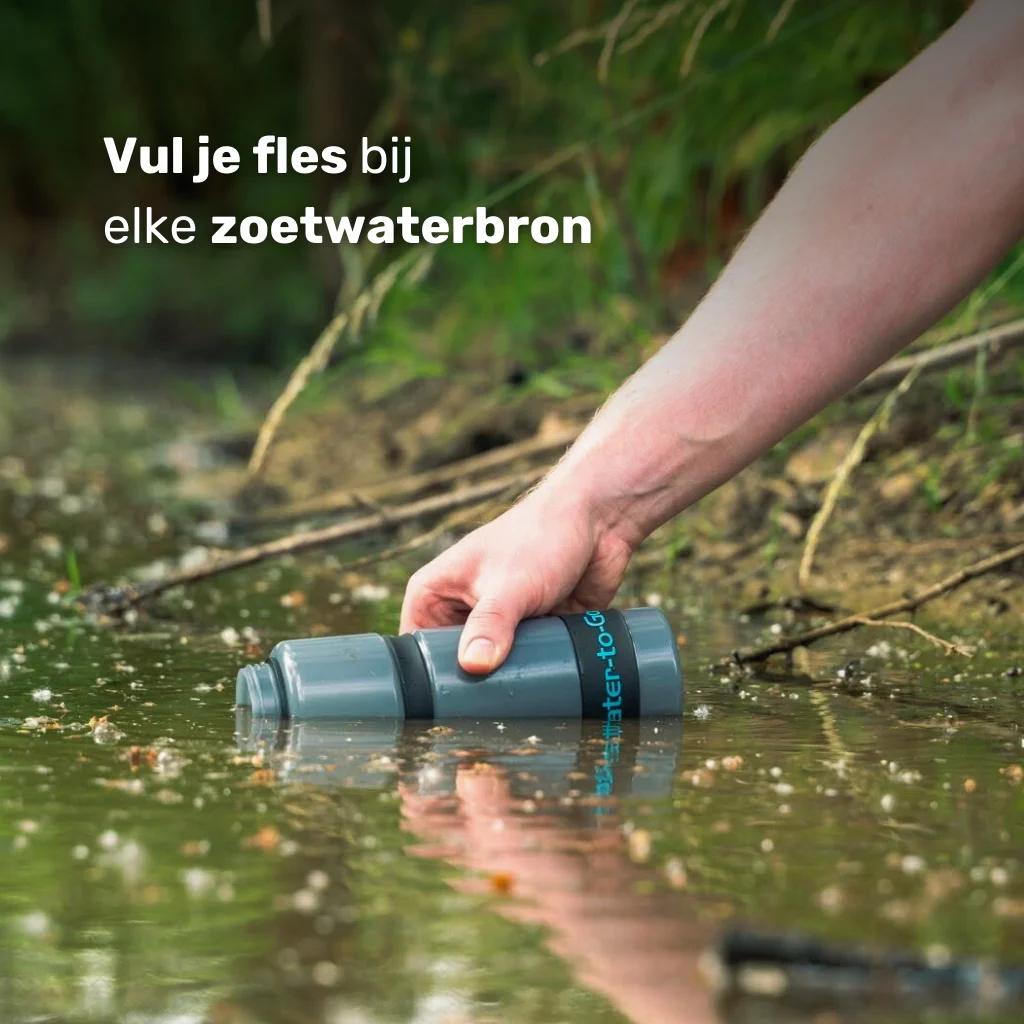 Hand vult de Water-to-Go Eco-Active 75cl outdoor waterfilter fles uit een rivier, beekje of meer