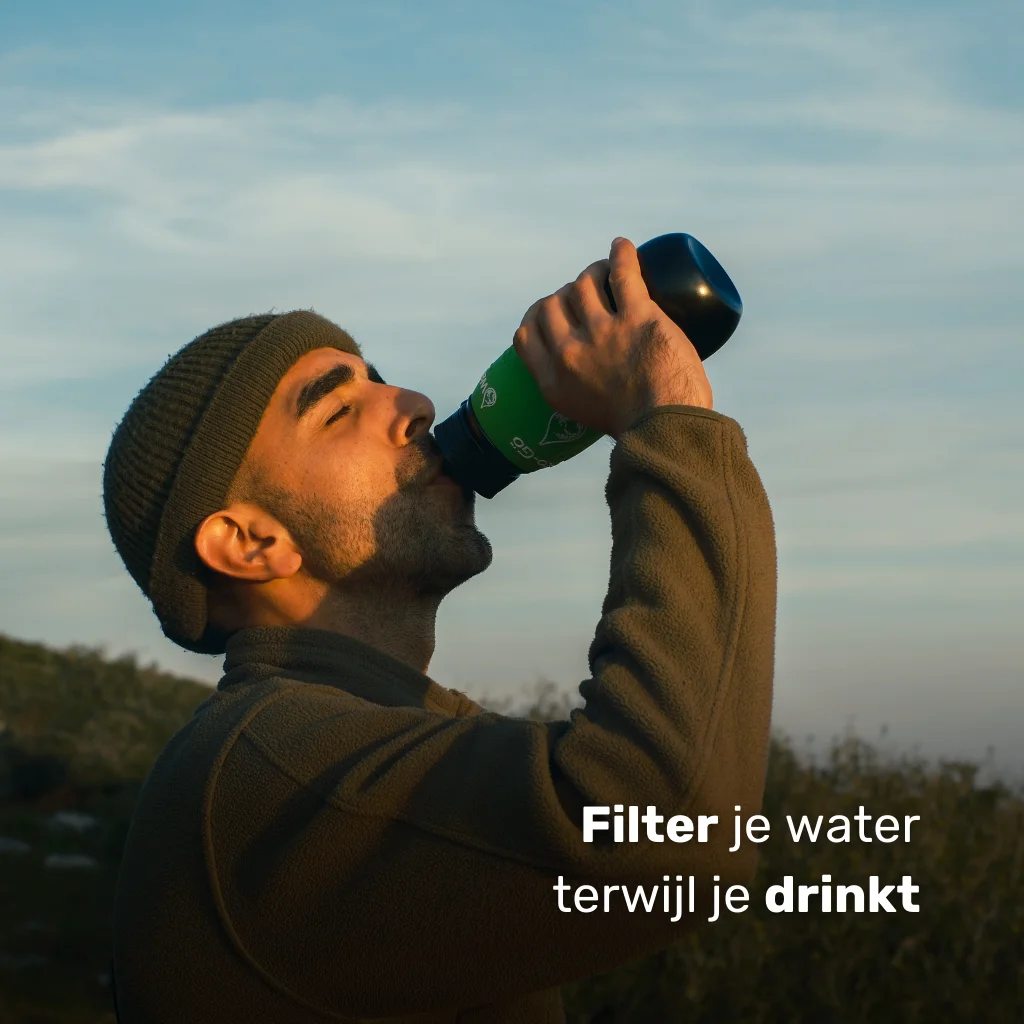 Man drinkt uit de BPA-vrije waterfles van Water-to-Go midden in de natuur en filtert zijn water terwijl hij drinkt.